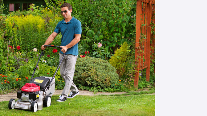 Honda IZY-grasmaaiers, driekwart vooraanzicht, zicht op linkerkant, in gebruik door model, tuinlocatie.