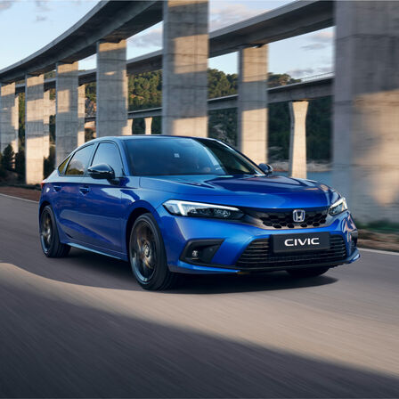 Driekwart vooraanzicht Honda Civic e:HEV hatchback, rijdend op de weg.