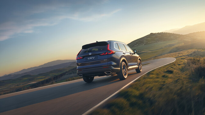 Zijaanzicht achterkant van blauwe CR-V Hybrid SUV auto in berggebied.