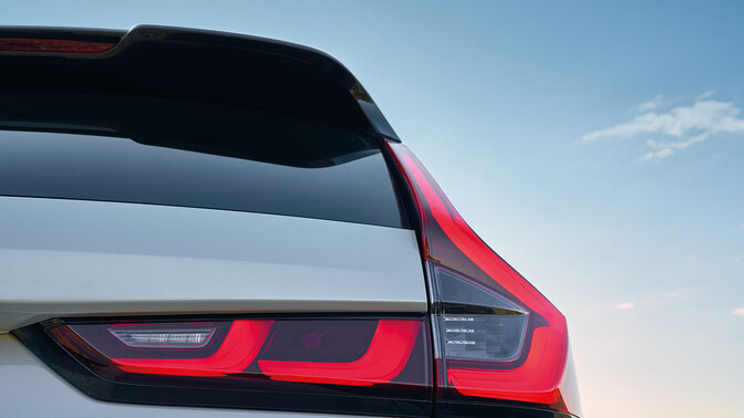 Zijaanzicht achterkant van blauwe CR-V Hybrid SUV auto in berggebied.