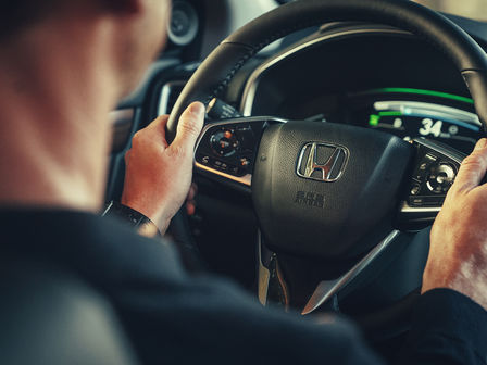 Close-up van model achter het stuur van Honda CR-V Hybrid.