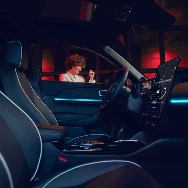 Verlicht interieur van de Honda e:Ny1 's nachts met model buiten het raam.