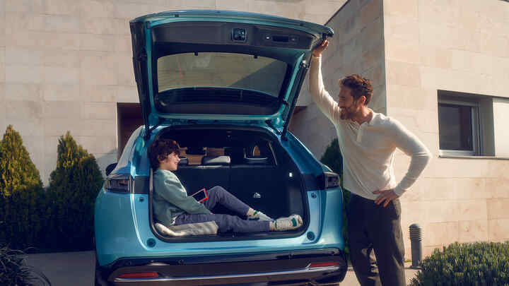 Vader in gesprek met kind zittend in de koffer van de Honda e:Ny1.