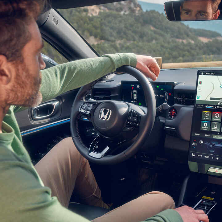 Man rijdt in de Honda e:Ny1 met navigatie weergegeven op het digitale display.