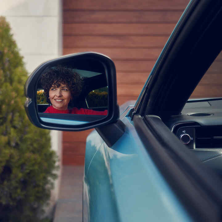 De reflectie van een vrouw in de buitenspiegel van de Honda e:Ny1.