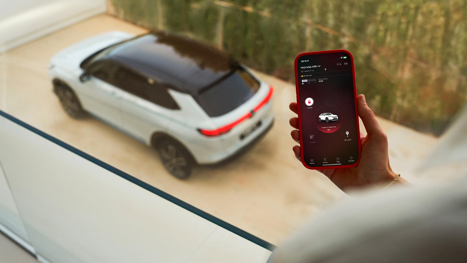 A person holds a smartphone displaying a vehicle charging settings app while a white SUV is parked in the background.