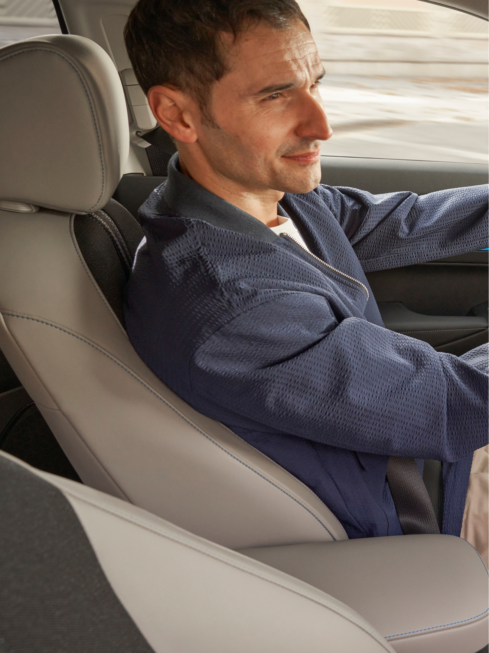 A driver sits behind the wheel of a Honda HR-V, viewed from the front passenger side, with the interior dashboard and a navigation map displayed on the center screen.