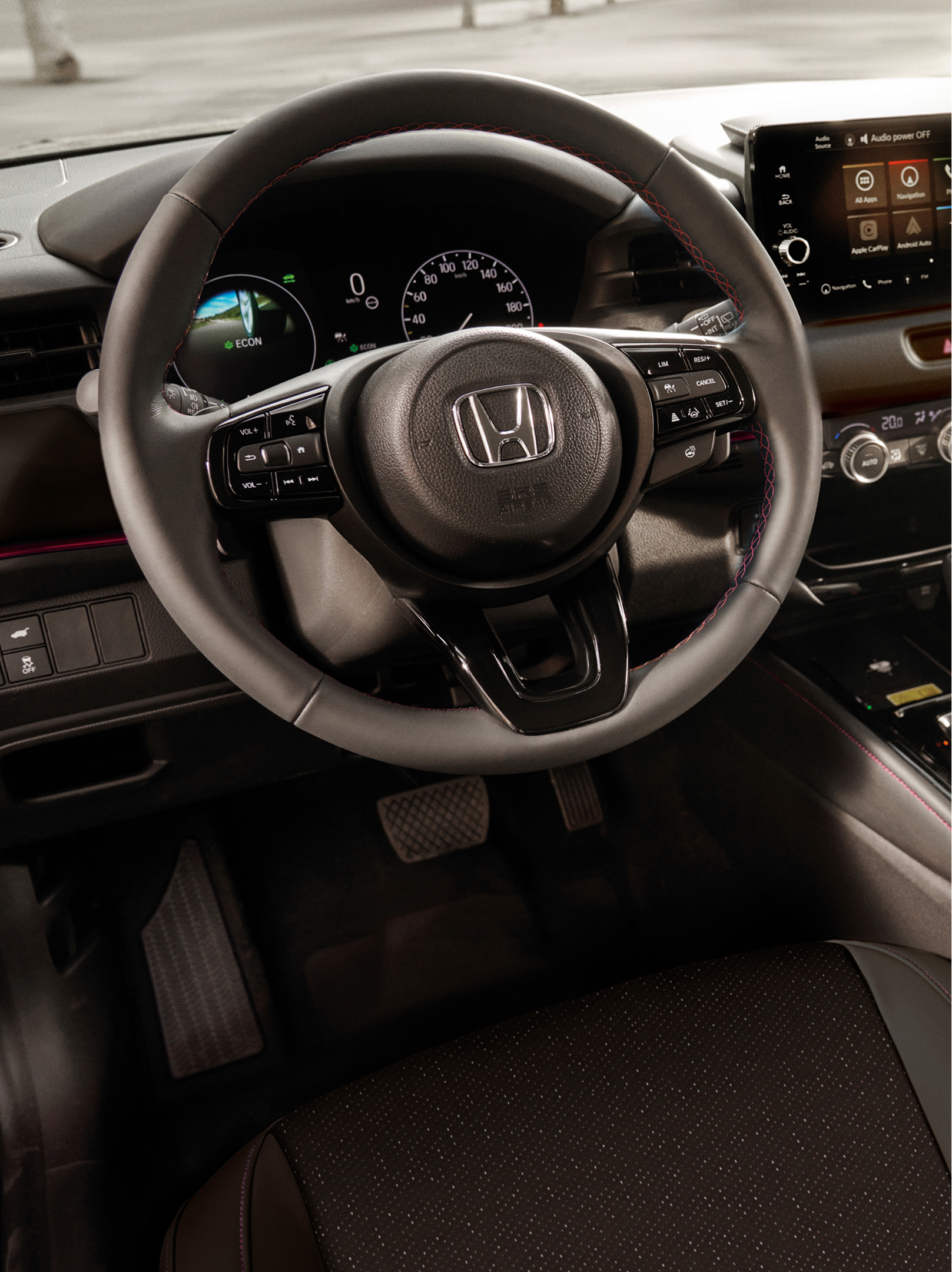Interior view of a Honda HR-V showing the steering wheel, digital instrument cluster, center touchscreen, and automatic gear selector.