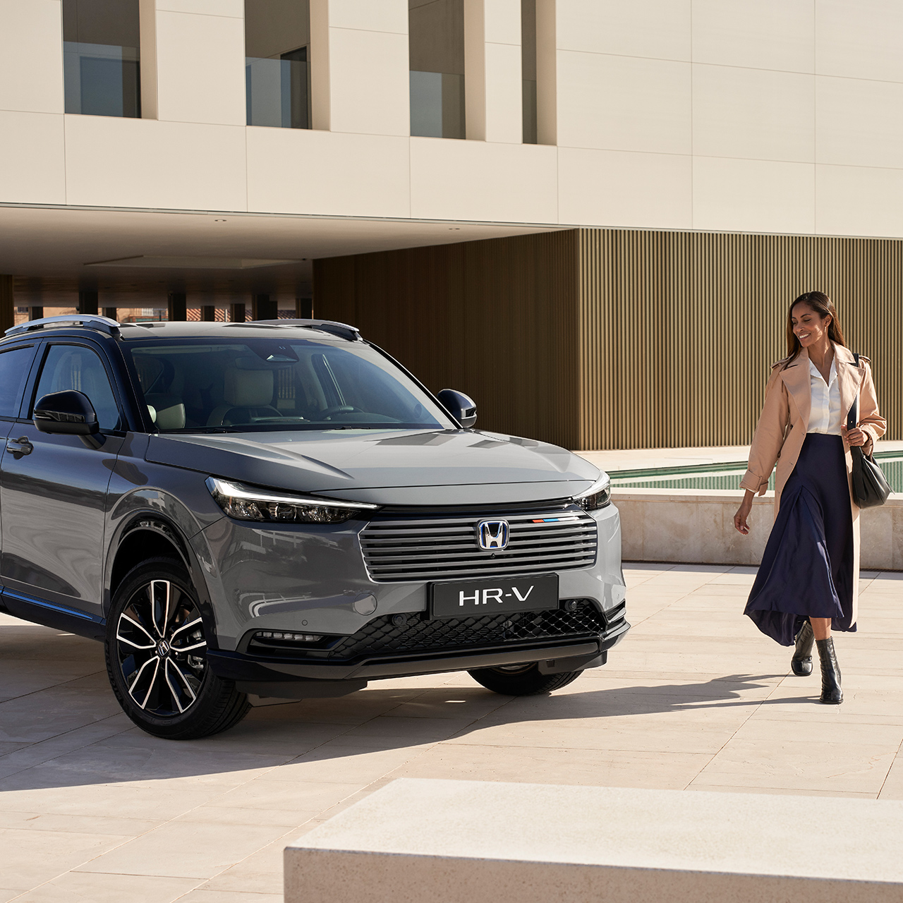 Koppel loopt naast geparkeerde HR-V buiten een gebouw. 