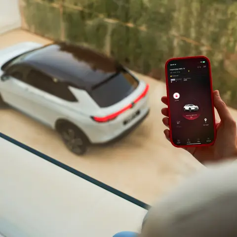 Close-up van persoon met telefoon die de My Honda + app gebruikt terwijl de Honda HR-V buiten het raam staat
