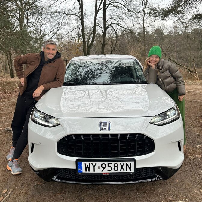 Two influencers leaning on the Honda ZR-V.