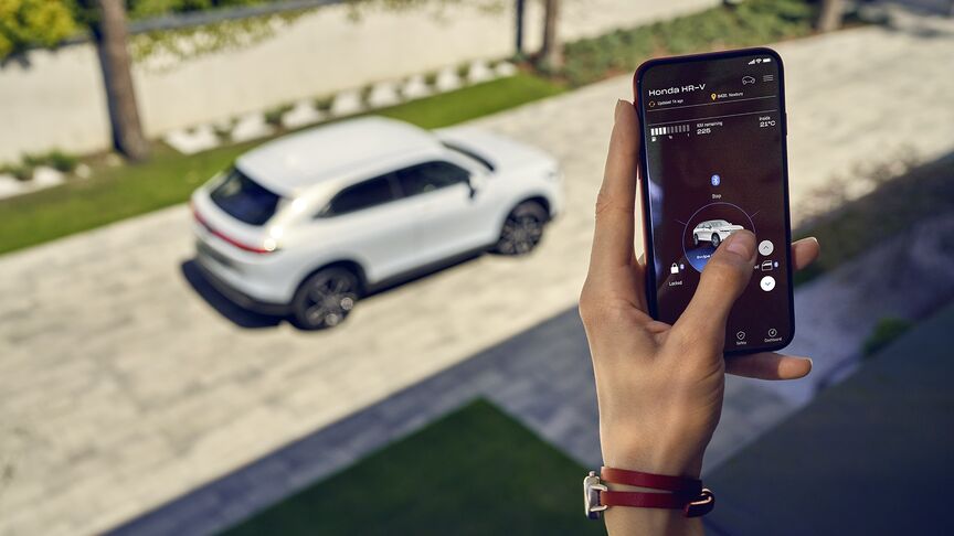 Een dame staat naast witte Honda e en gebruikt de My Honda+ app
