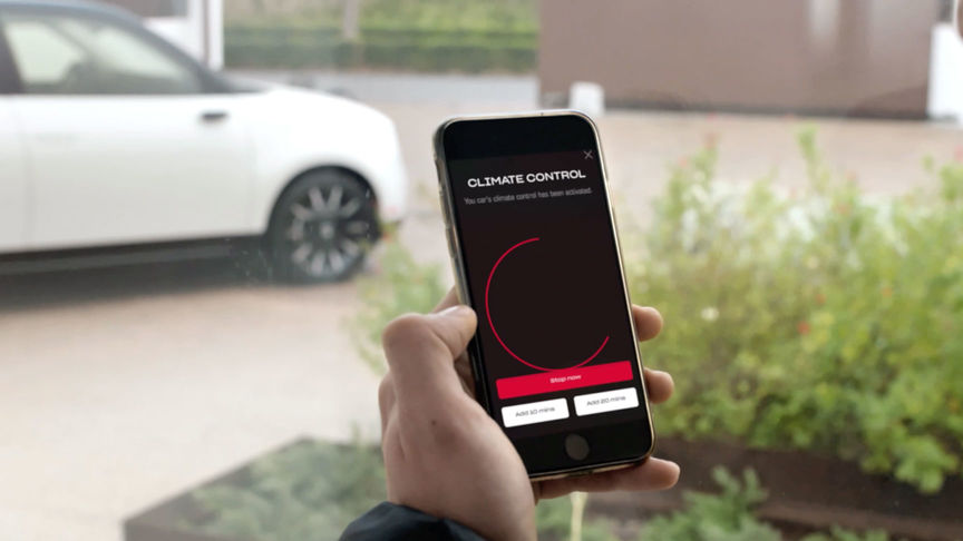 Een man kijkt naar de My Honda+ app met een Honda Jazz Hybrid Crosstar op de achtergrond. 