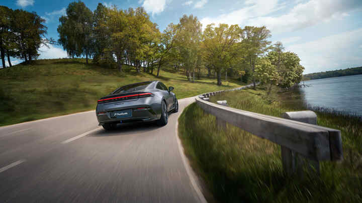 Achteropname van een Honda Prelude Hybrid rijdend op een snelweg, naast een meer.