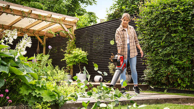 Vrouw met accu bladblazer in tuin