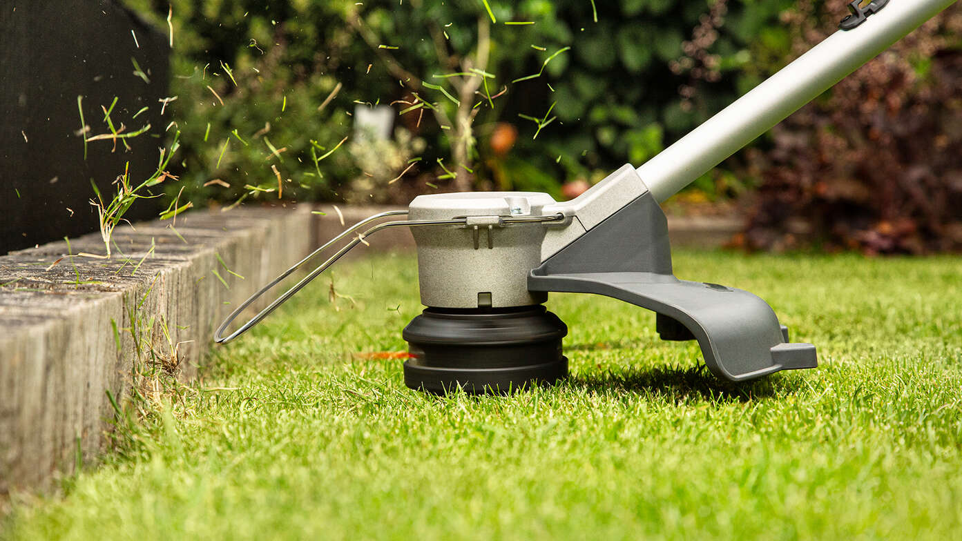 Accu Honda grastrimmer trimt de zijkant van het gras in de tuin.