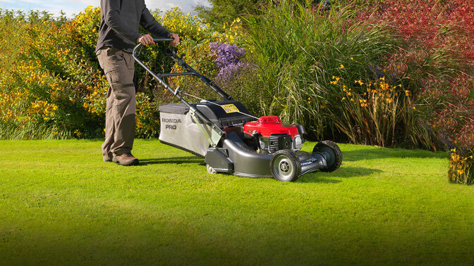 Man die gras maait met Honda HRH grasmaaier in de tuin