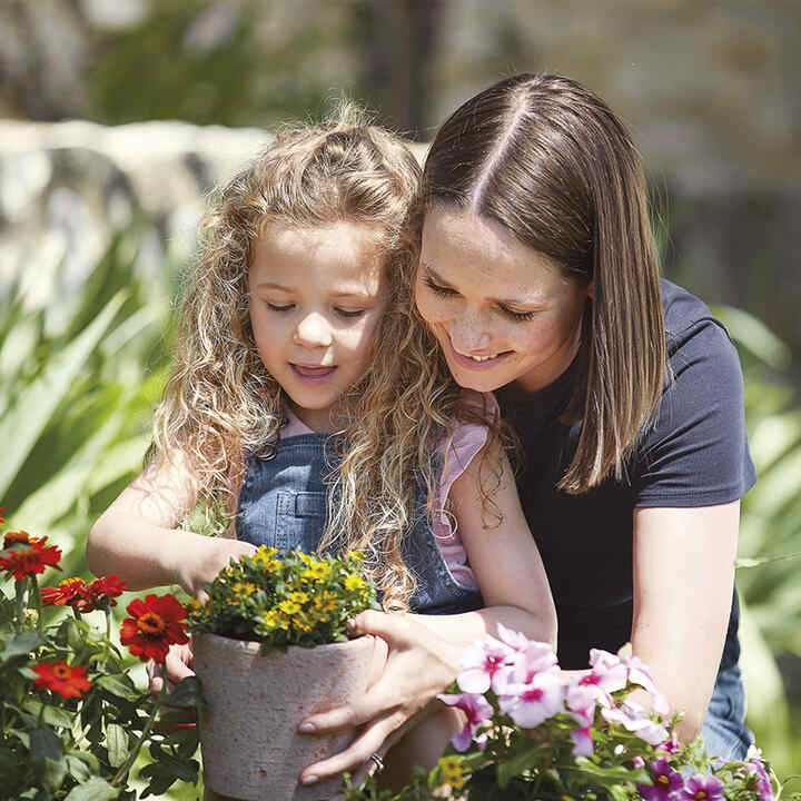 Moeder en dochter planten bloemen.