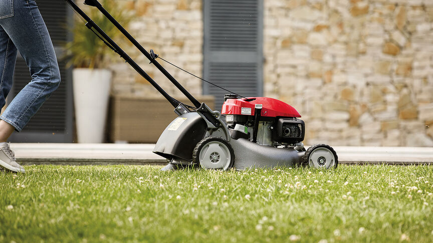 Honda IZY grasmaaier zijaanzicht met vrouw in tuin