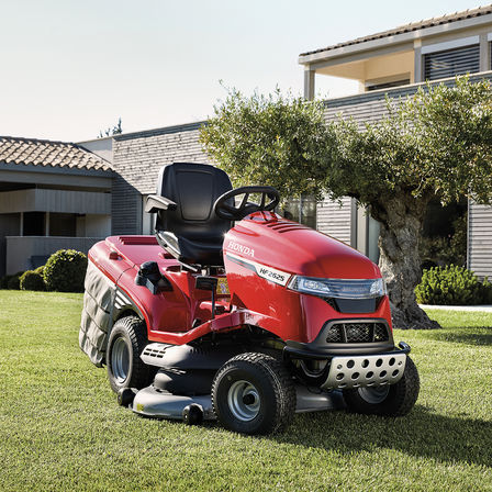 Driekwart vooraanzicht Honda zitmaaier in een tuin met huis op de achtergrond