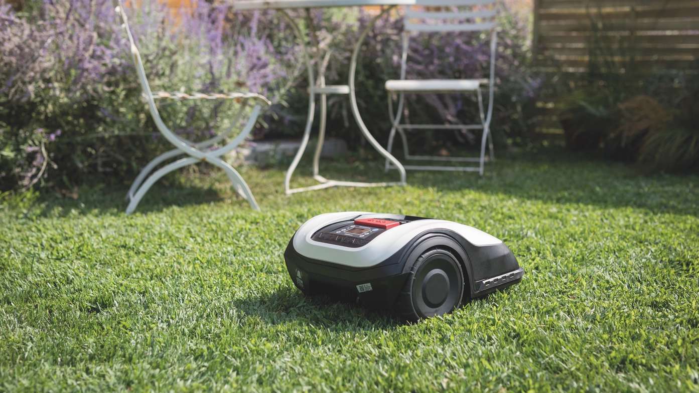 Driekwart achteraanzicht van Honda Miimo in een tuin met een tafel en stoelen op de achtergrond.
