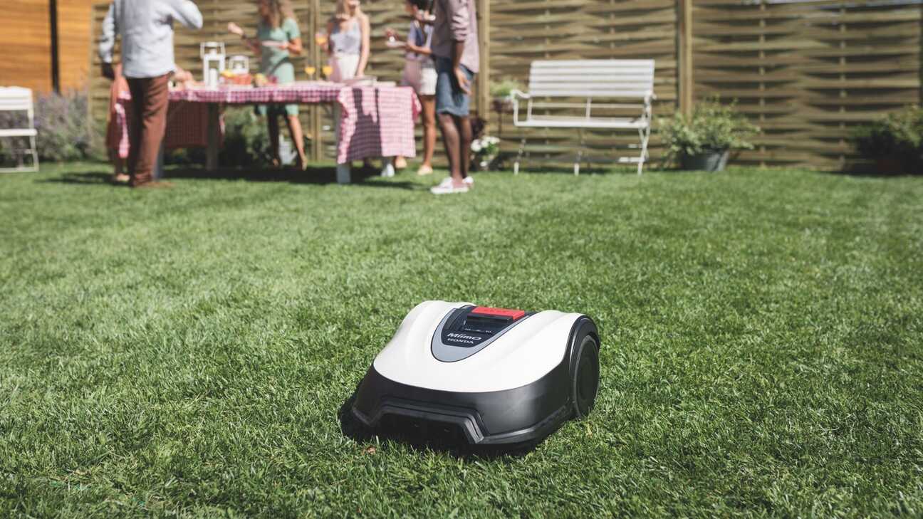 Driekwart vooraanzicht van Honda Miimo in een tuin met figuranten en meubels op de achtergrond.