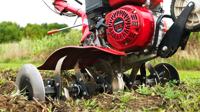 Close-up van compacte tuinfrees, met focus op motor, tuinlocatie.