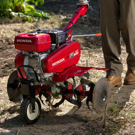 Close-up van compacte tuinfrees, met focus op transportwiel, tuinlocatie.