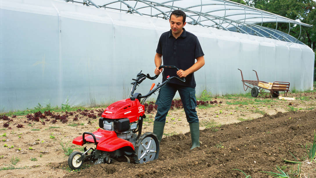Roterende tuinfrees, in gebruik door model, tuinlocatie.