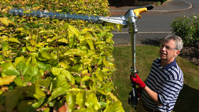 Honda Versatool met heggenschaaropzetstuk, in gebruik door model, tuinlocatie.