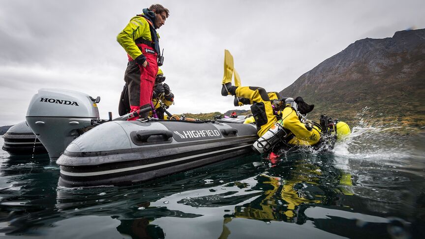 Man in een boot met een BF15 motor langs de kust. 