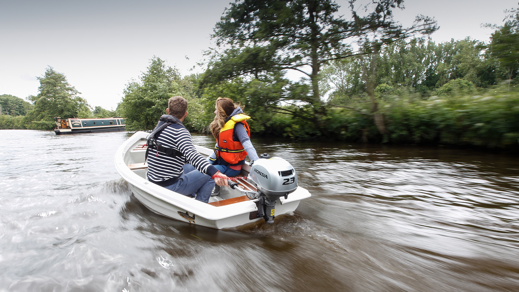 Twee mensen in een boot met de BF2.3 motor, naast een kanaalboot.