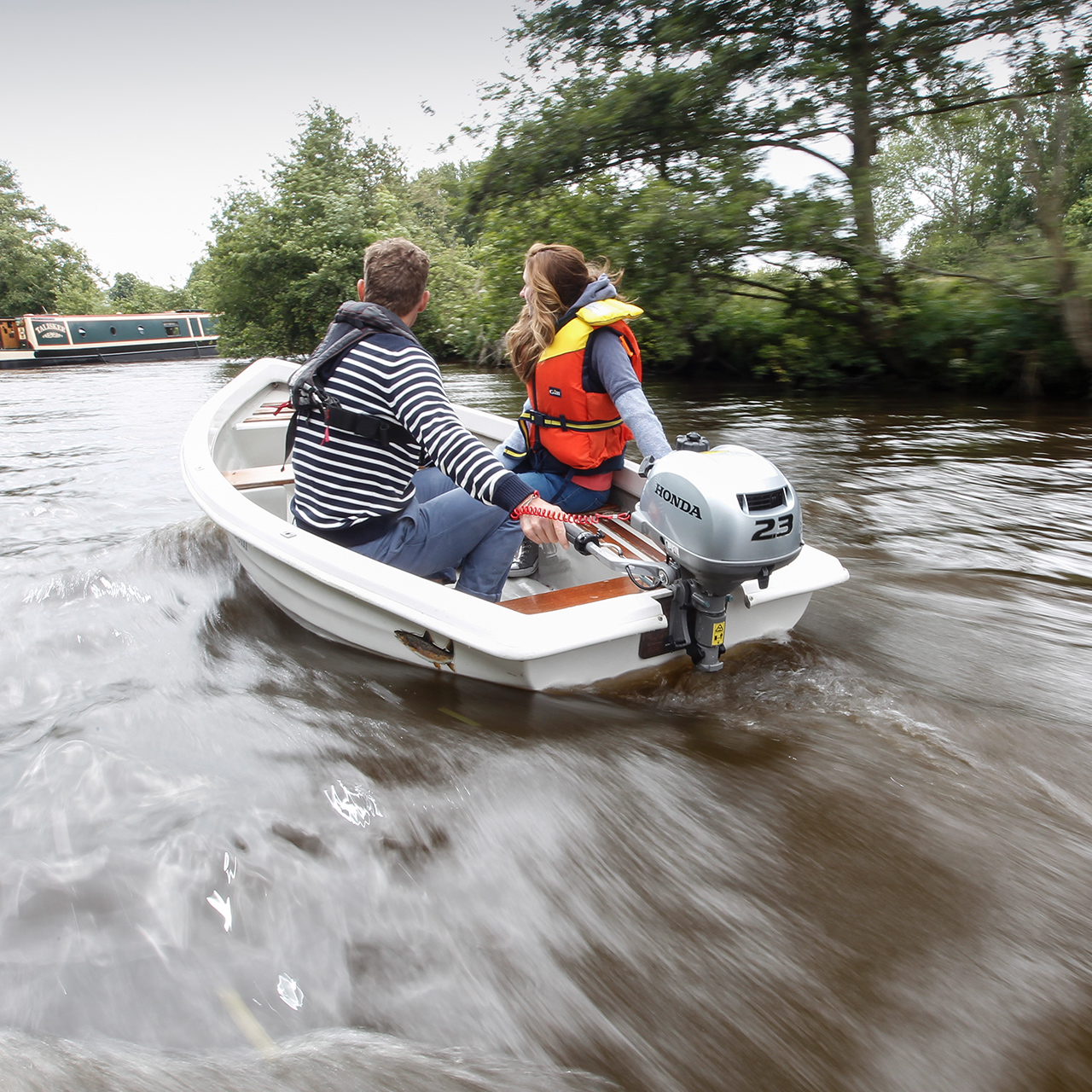 Twee mensen in een boot met de BF2.3 motor, naast een kanaalboot.