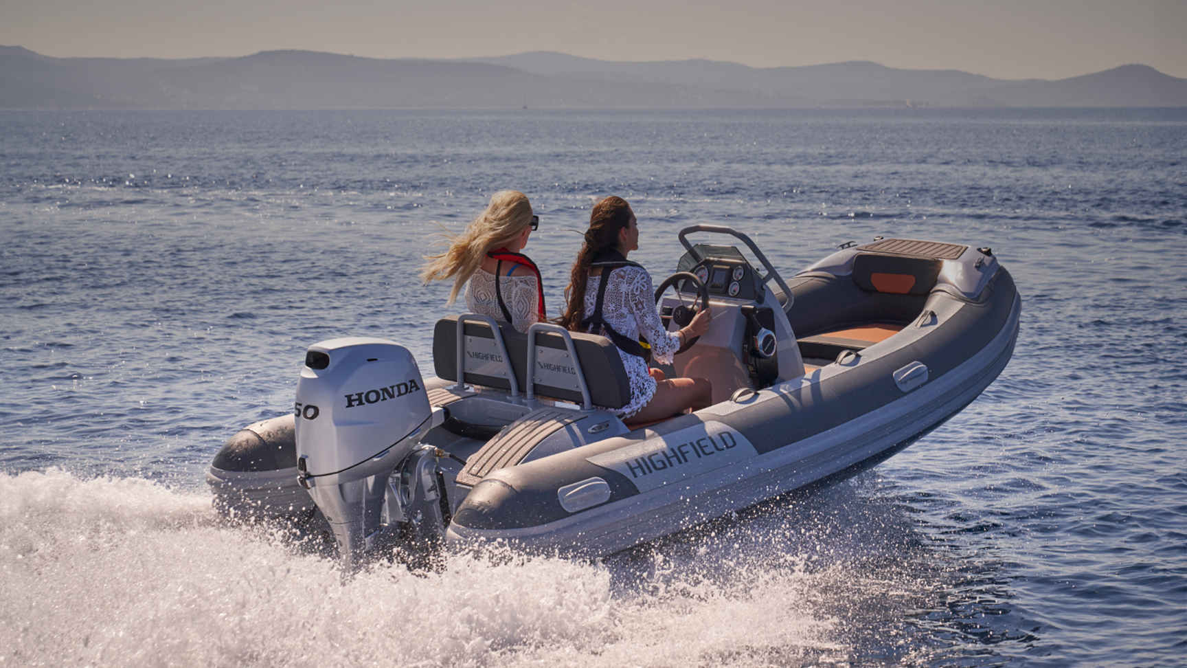 Twee modellen in een Highfield boot met Honda BF50 motor op zee.