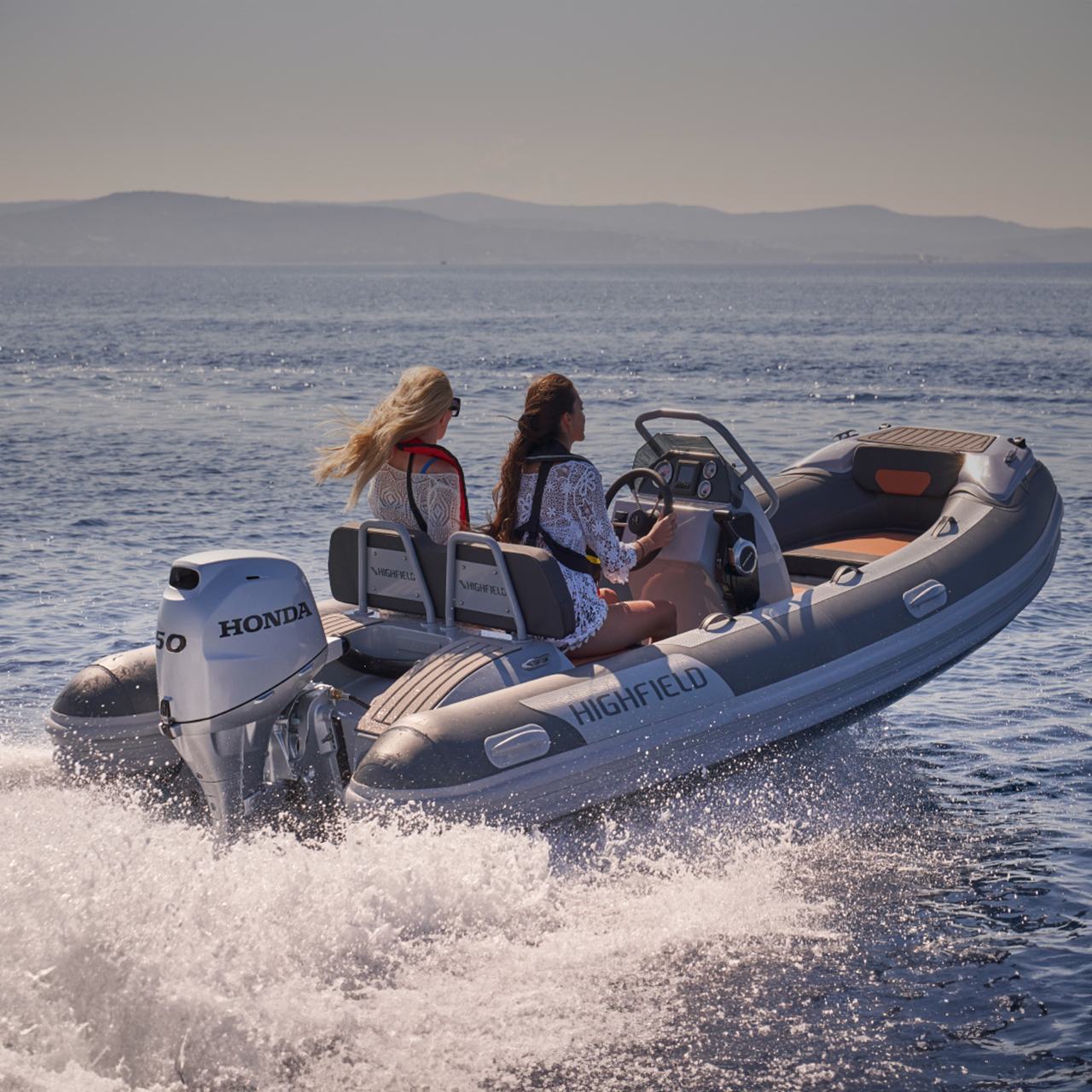 Twee modellen in een Highfield boot met Honda BF50 motor op zee.
