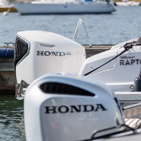 Close-up van Honda motoren achter op boten in het water. 