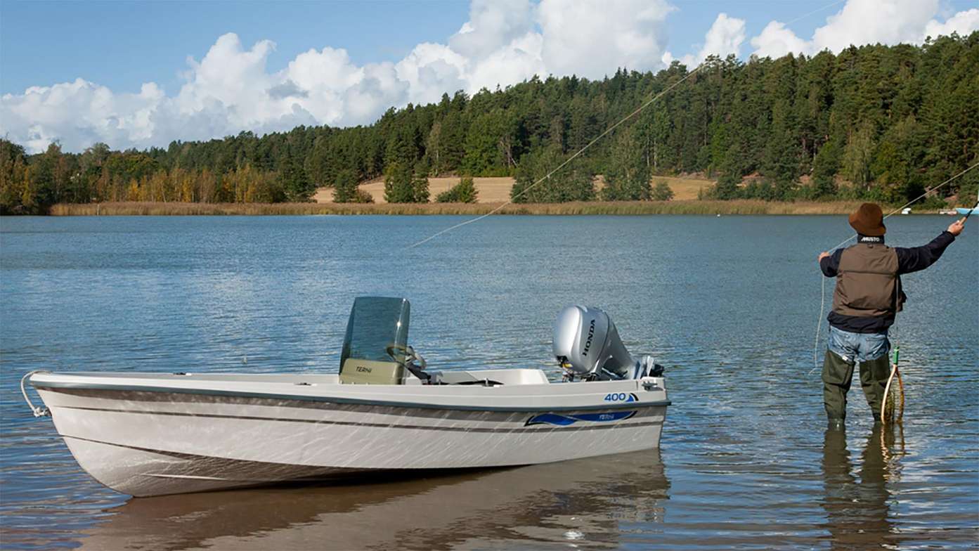 Man aan het vissen naast een kleine boot met een Honda buitenboordmotor