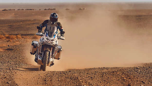 Rijder in vooraanzicht op Honda CRF1100 Africa Twin Adventure Sports in woestijnomgeving.