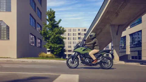 Zijaanzicht van een model rijdend op de NC750X in een stadsomgeving.