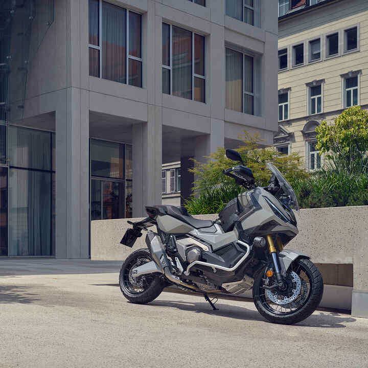 X-ADV-motorfiets geparkeerd op oprit in stedelijke omgeving.