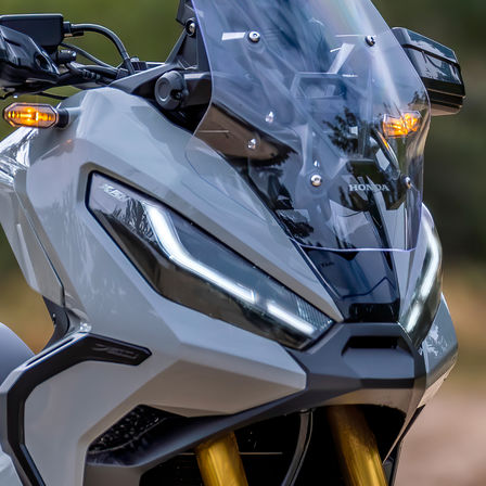 Honda X-ADV, driekwart vooraanzicht, geparkeerd met rijder, grijze motor