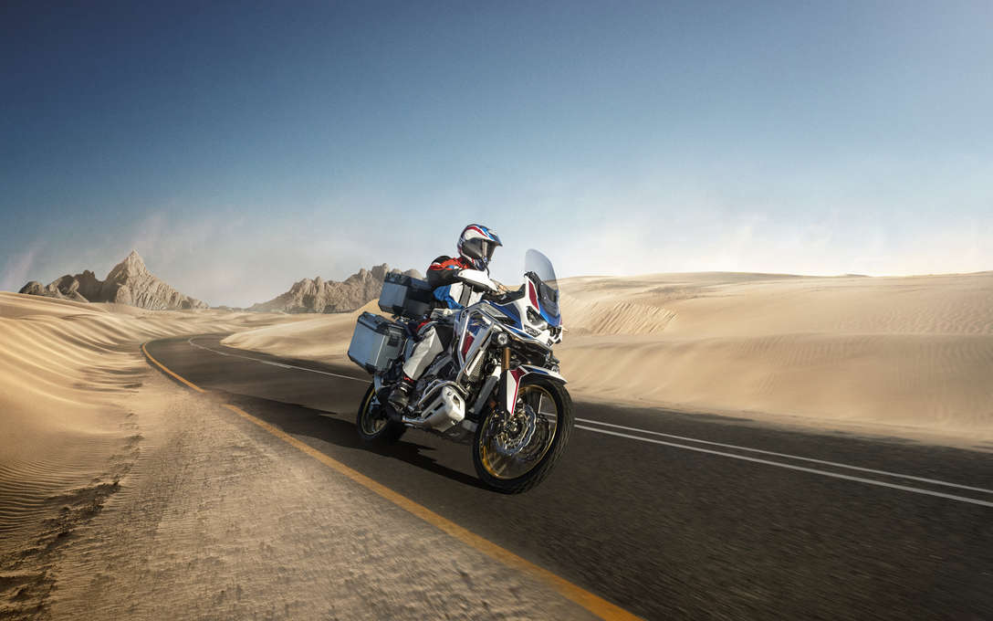 Honda Africa Twin Adventure Sports, 3-kwart voorkant rechts, rijdend op een weg door een woestijnlandschap