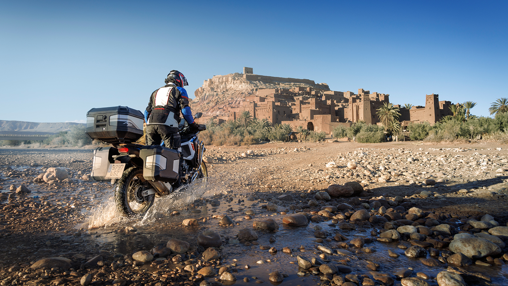 Achteraanzicht rijder die naar CRF1100 ATAS met touringaccessoires kijkt.