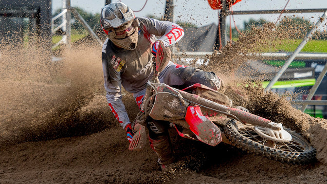Vooraanzicht Honda offroad motorfiets met rijder, glijdend door modder.