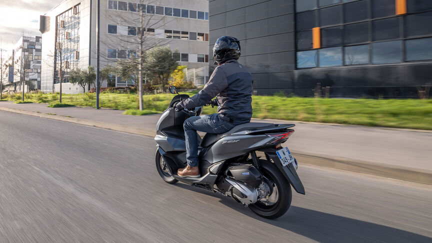 Honda PCX125 - driekwart achteraanzicht dynamisch met rijder