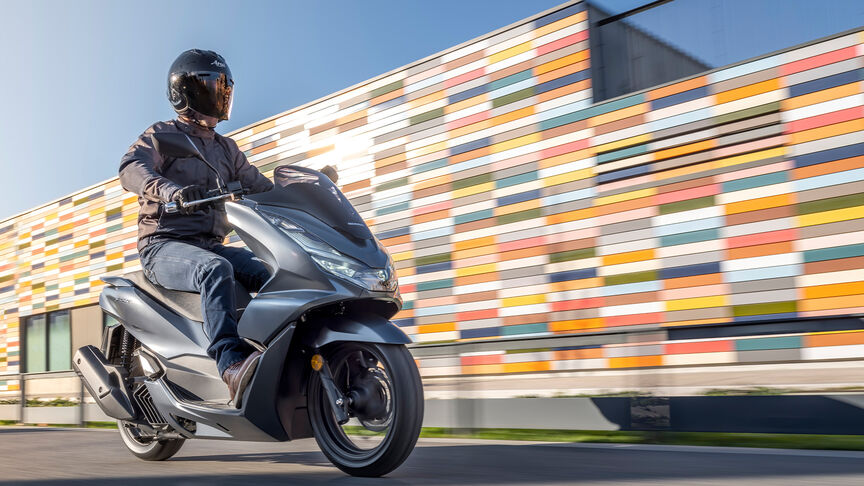 Honda PCX125 - driekwart achteraanzicht dynamisch met rijder