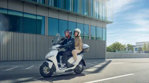 Modellen rijdend op de Honda CUV e motorfiets in een stedelijke omgeving.