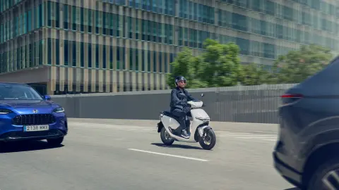 Rijder op een Honda CUV e in een stedelijke omgeving.