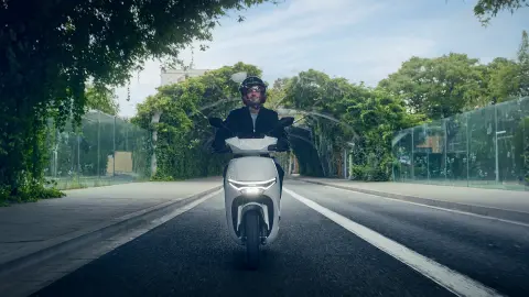 Vooraanzicht van een model dat rijdt met de Honda CUV e motorfiets in een stedelijke omgeving.