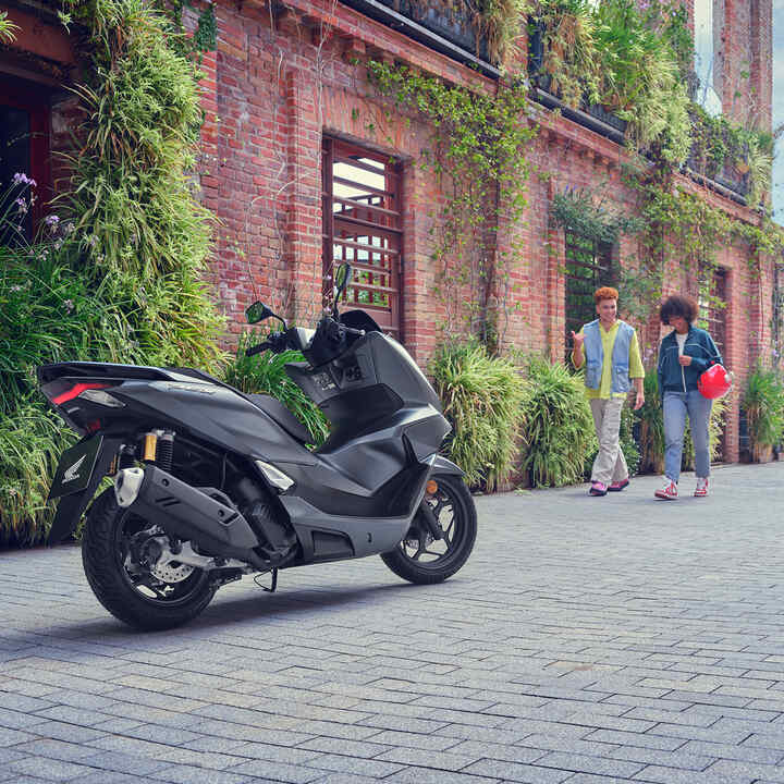 Model wandelt richting de PCX125 motorfiets.
